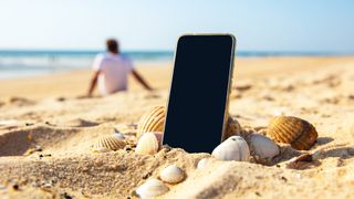 Mobile phone on the beach with a person relaxing in the background