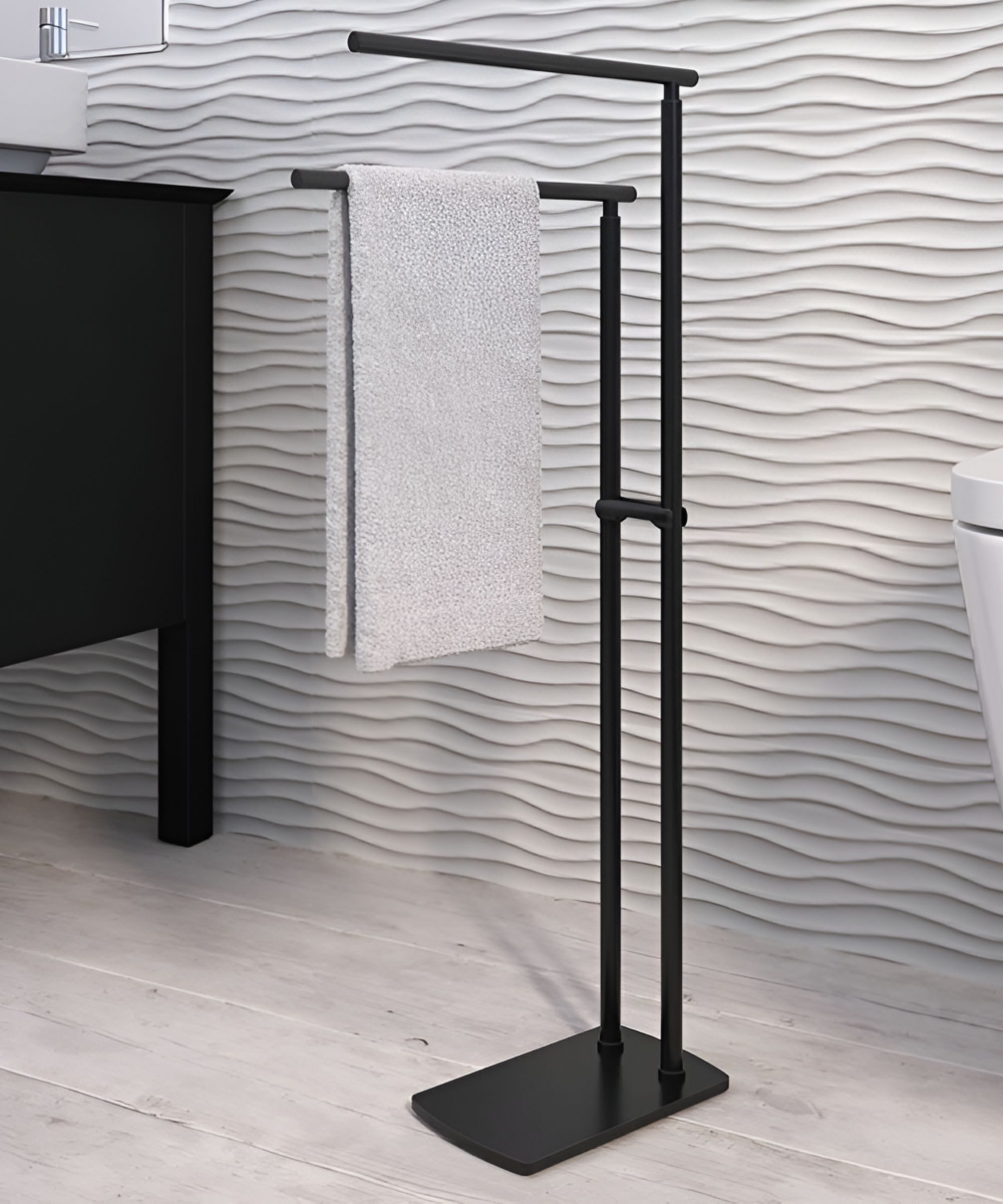 A freestanding matte black towel stand offers a compact solution beside the basin. Clean lines and a textured wall tile backdrop create a modern, minimalist look.