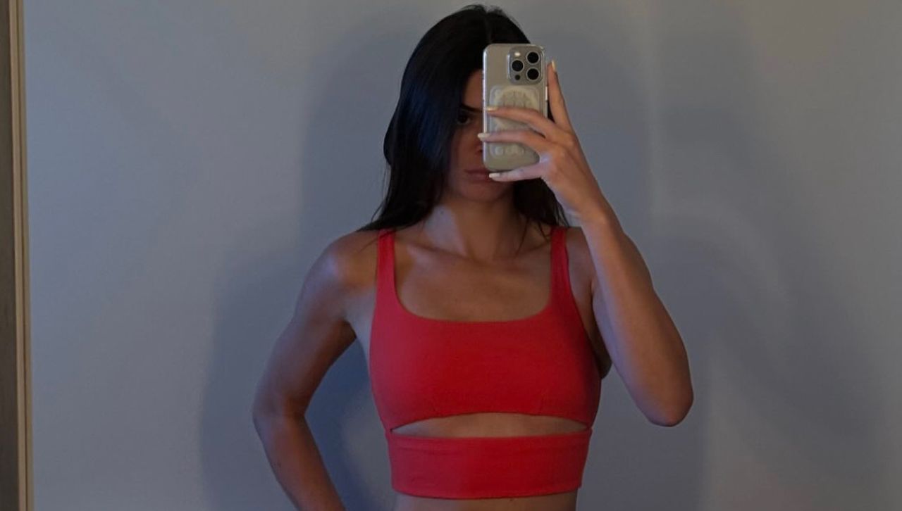 Kendall Jenner wears a red alo yoga set in front of a plain wall