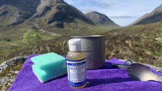 Camping dishes and washing up supplies for camping laid out with mountains in the background