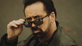 Nicolas Cage looking over a pair of sunglasses, looking cool, and wearing a leather jacket in Willy's Wonderland, 2018.