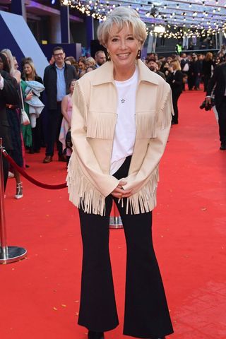 Emma Thompson wearing black flared trousers and a fringed jacket