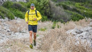 A man in a waterproof jacket running along a trail