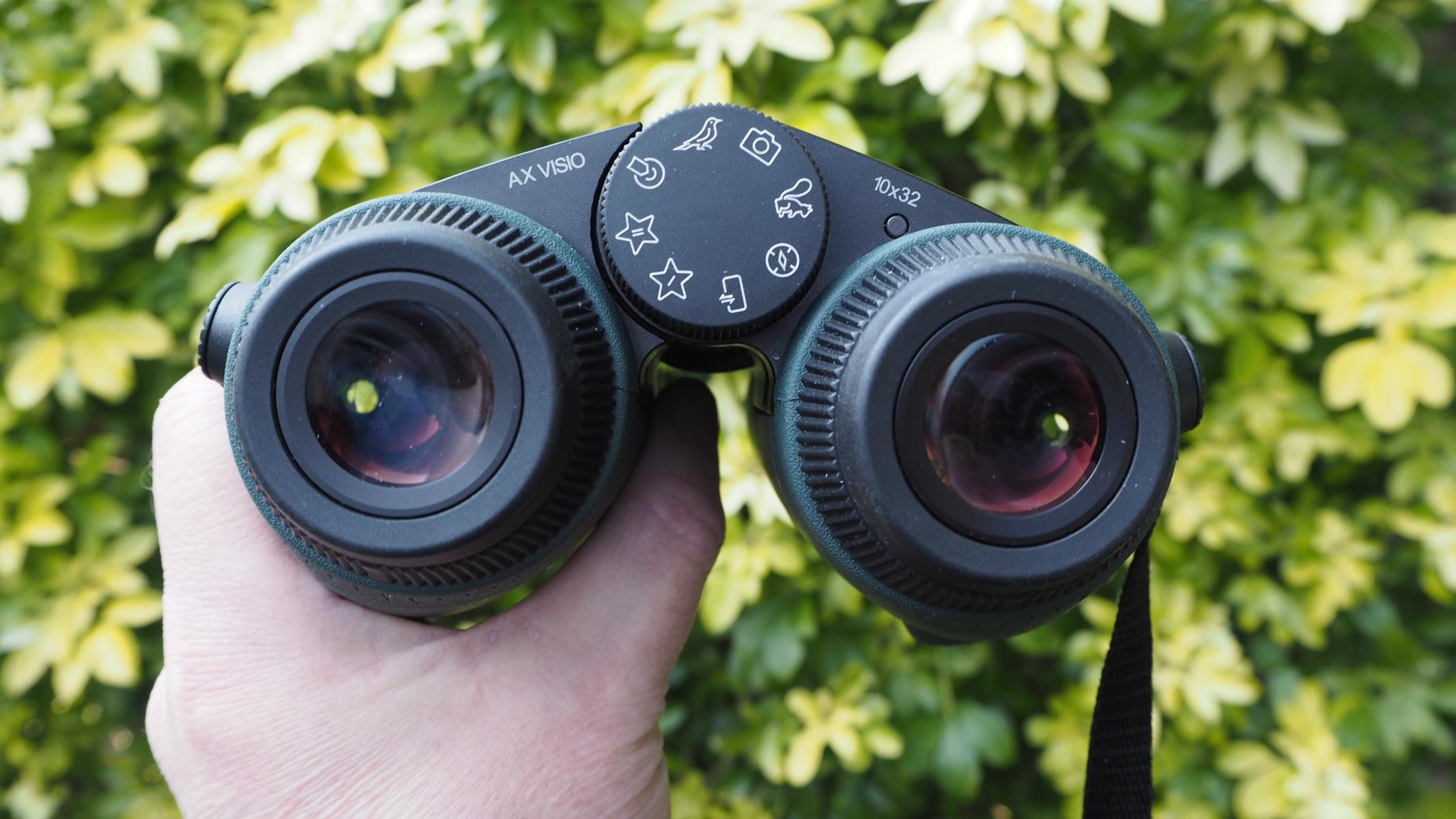 A pair of Swarovski Optik AX Visio smart binoculars, held in a hand.