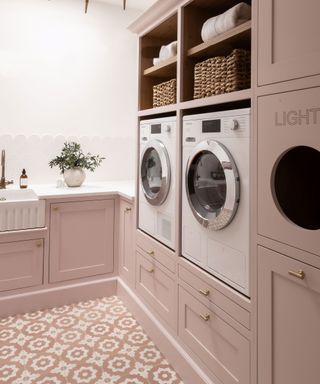 pink laundry room with built in washer and dryer and pink patterned floor tiles