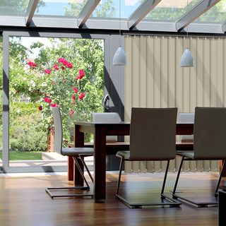 A modern conservatory with vertical blinds and a dining table