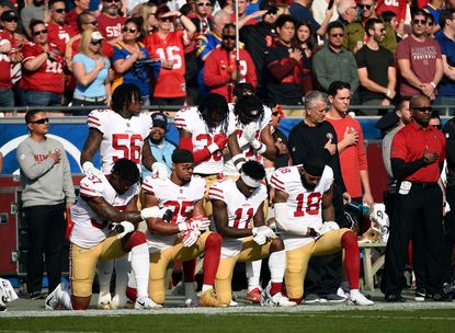 Several members of the San Francisco 49ers kneel during the national anthem