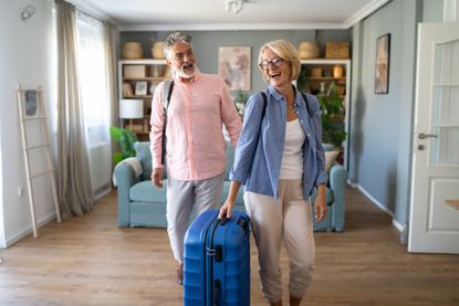 Couple Standing With Suitcase About To Leave For Vacation