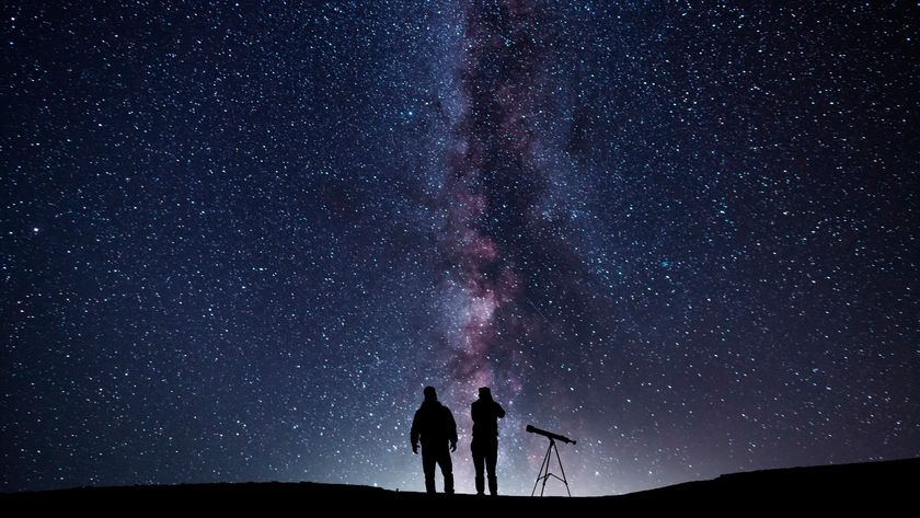 two people with a telescope under the milky way