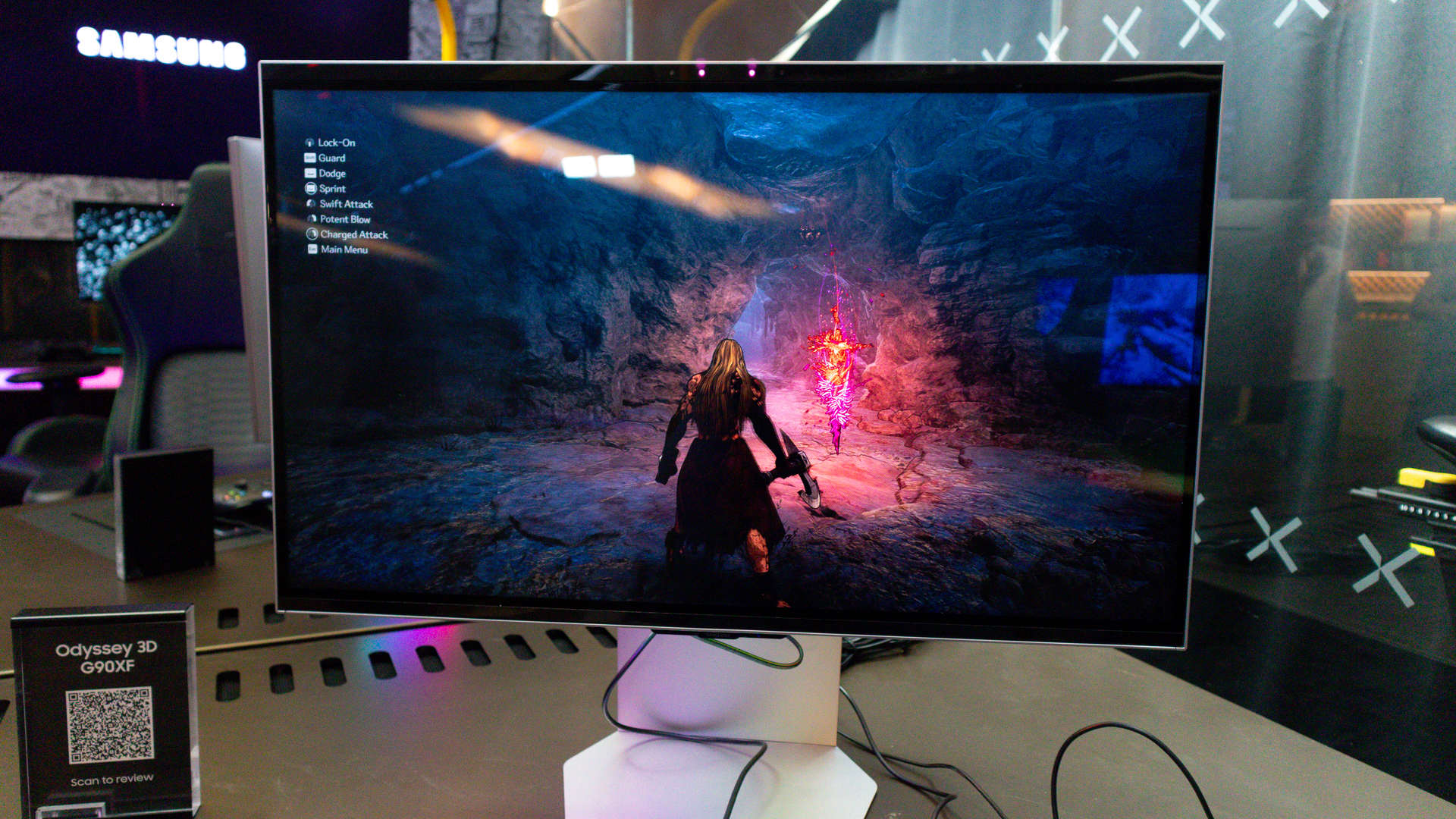 Samsung Odyssey 3D monitor on a desktop with keyboard, Xbox controller and other gaming accessories