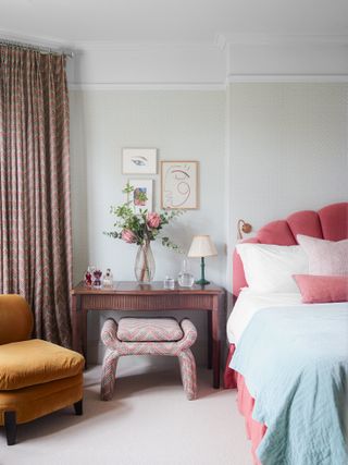 Bedroom with pale blue wallpaper and pink velvet headboard