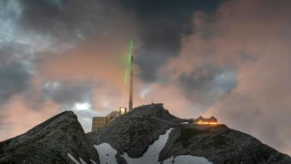 The infrared laser beam fishes for lightning in the sky above Switzerland's Säntis mountain.