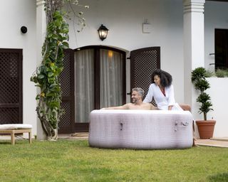 two people sitting inside and on the edge of a hot tub on a patio