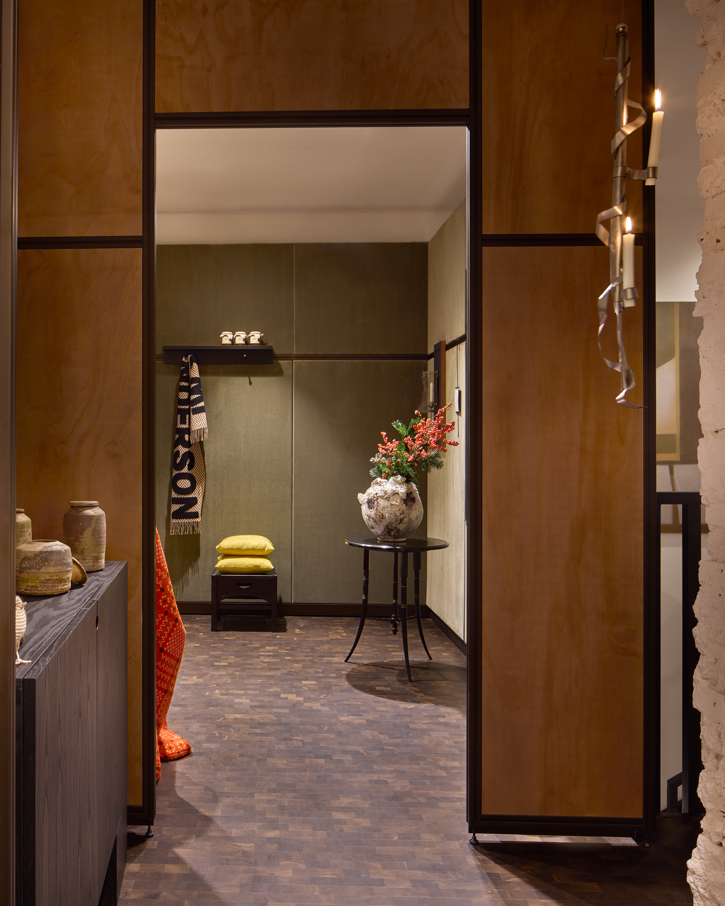 Image of a interior store showroom with wood paneled doorway that leads to a room with white and sage green paneled walls.