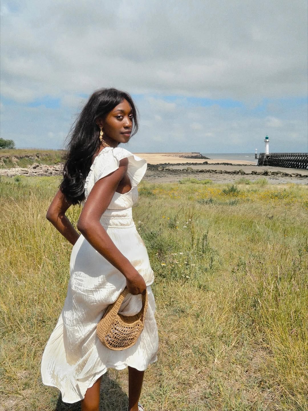 Emmanuelle in a white summer dress and with a raffia bag