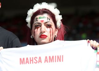 DOHA, QATAR - NOVEMBER 25: An Iran fan holds a shirt in protest with the name Mahsa Amini who died under Police custody during the FIFA World Cup Qatar 2022 Group B match between Wales and IR Iran at Ahmad Bin Ali Stadium on November 25, 2022 in Doha, Qatar.