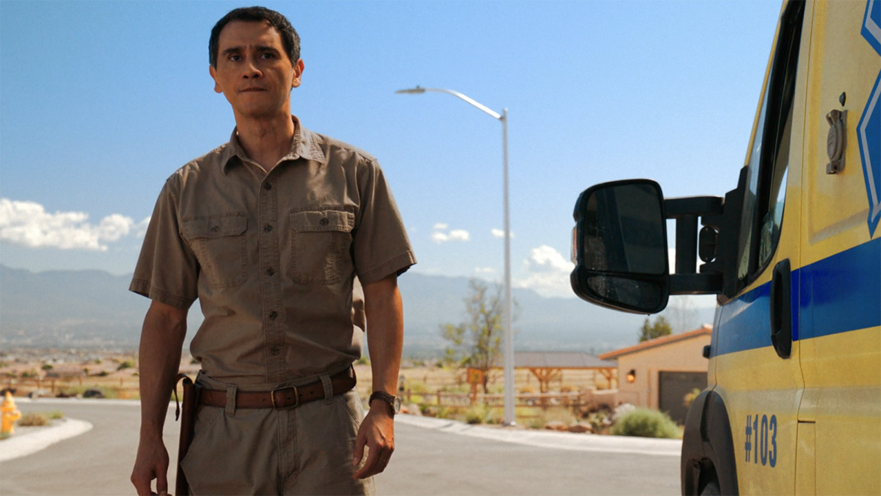 Manousos standing next to an ambulance in Pluribus episode 9