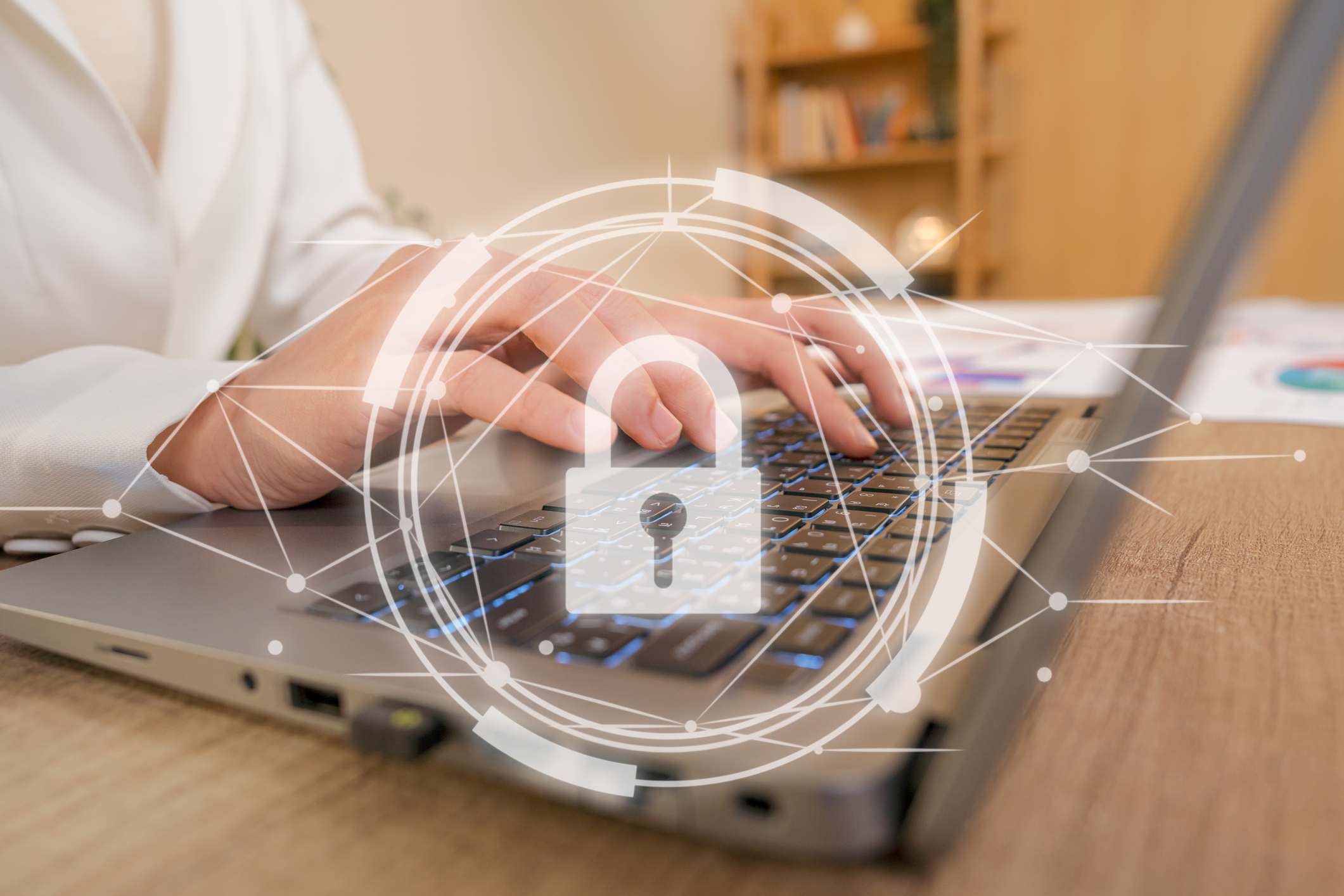 A person's hands typing on a laptop with a digital security padlock symbol overlaid.