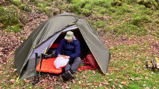 A man in a tent inflating a sleeping pad