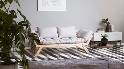Green futon bed, patterned cushions, ladder shelf, shelving unit