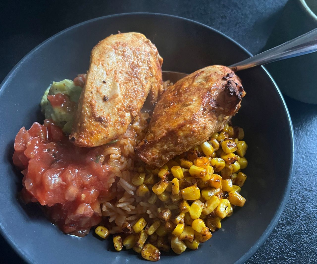 Cooked chicken breasts in a bowl with guac and salsa, and fried corn
