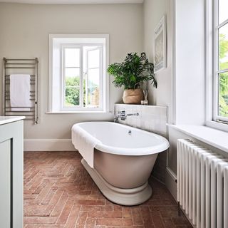 bathtub on stone flooring underneath shelving and windows