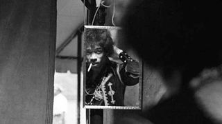 Reflection of American Rock musician Jimi Hendrix (born Johnny Allen Hendrix, 1942 - 1970) as he fixes his hair in a mirror backstage during a concert at Forest Hills Stadium, Queens, New York, New York, July 17, 1967.