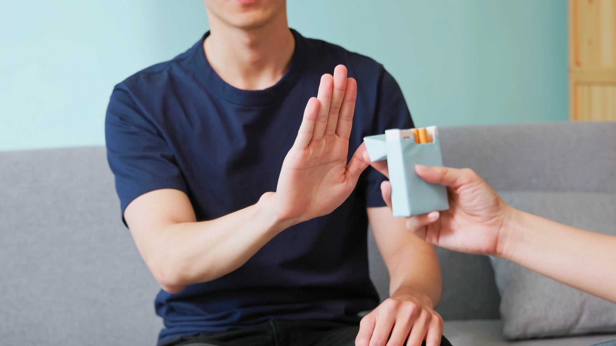 A young man refuses the offer of a cigarette.