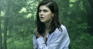 Emmy-nominated actor Alexandra Daddario as Rowan Fielding stands bloodied in a lush green forest in a scene from in supernatural TV series Mayfair Witches season 1.