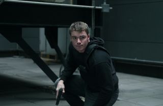 Gabriel Basso as Peter Sutherland in an all black outfit crouching in the night agent