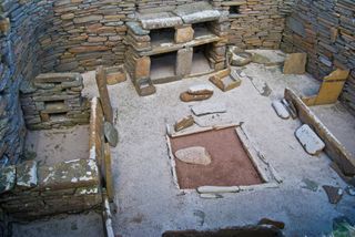 A dresser with stone shelves lines a wall in a house in Skara Brae.