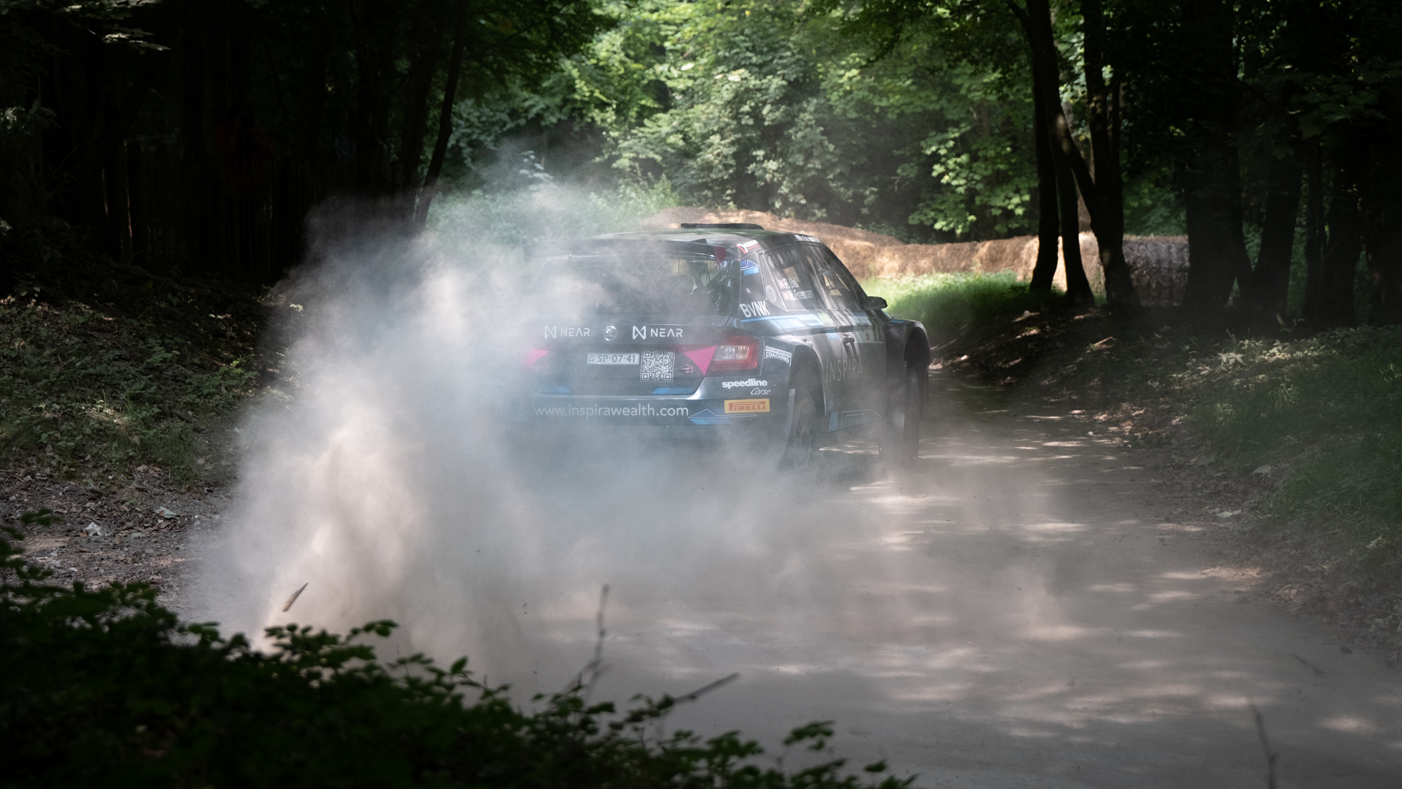 A rally car turning the corner of a race track at Goodwood