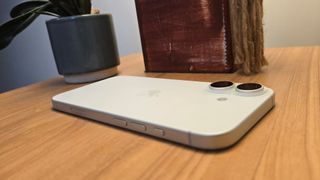 Apple iPhone 16 smartphone face down on wooden table