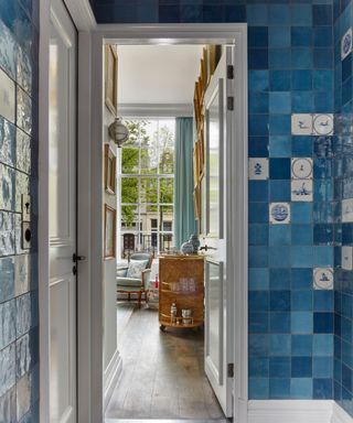 hotel bathroom with blue zellige tiles and a handful of handpainted delft tiles in the mix with a view through the door into the main bedroom suite