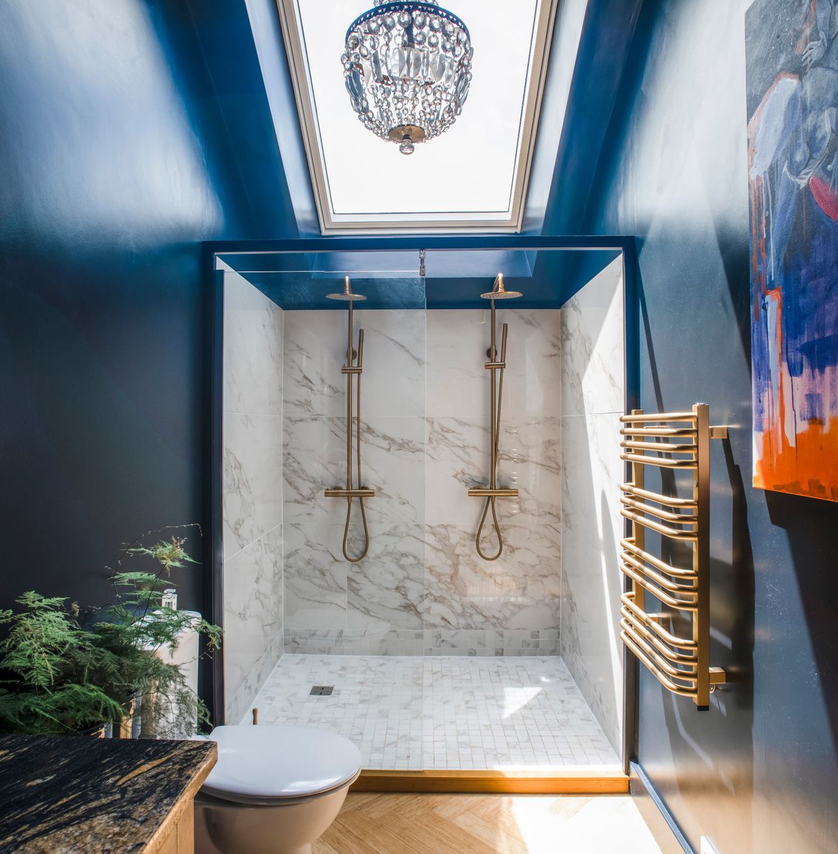 A shower with marble backsplash and brass fittings in a blue room