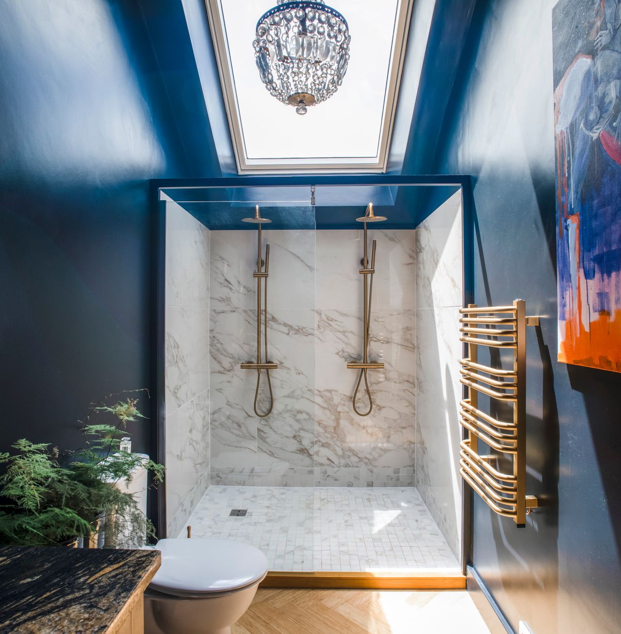 A shower with marble backsplash and brass fittings in a blue room