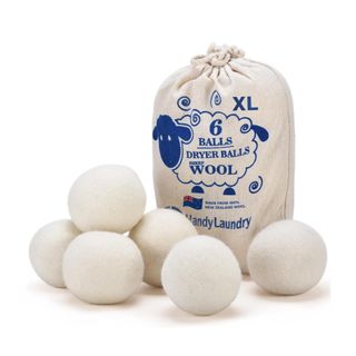 Five beige wool dryer balls, with a beige cloth bag next to them with a dark blue illustration of a sheep