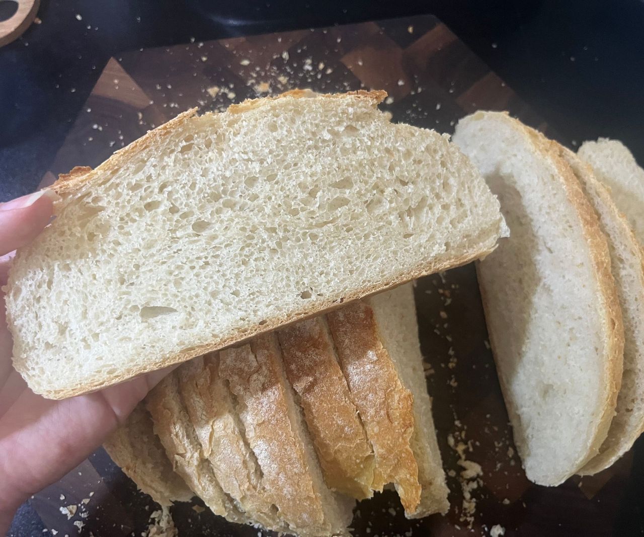 A slice of airy bread held above a sliced loaf