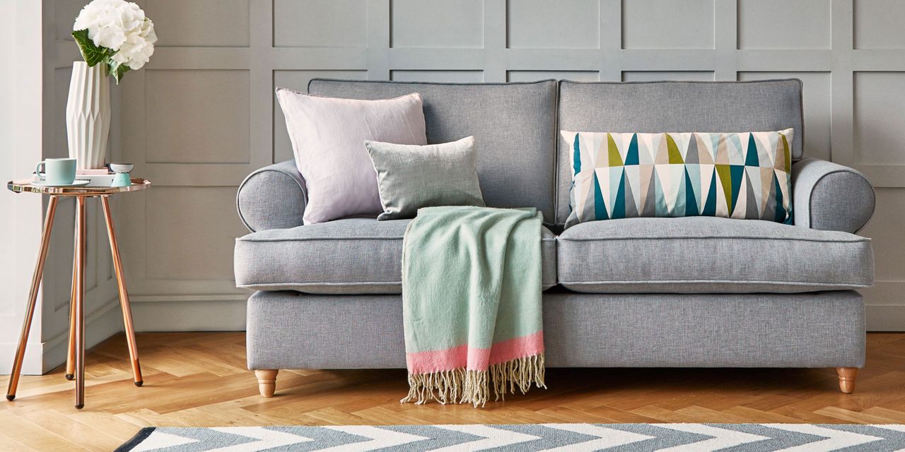 Grey sofa in living room with panelled wall and wooden floor 