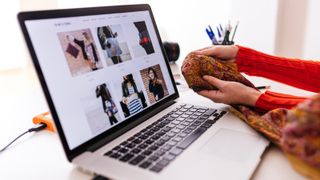 OOOOO - Close-up of fashion designer in studio with laptop examining fabric