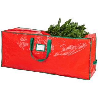 A red and green christmas storage bag with green straps and a christmas tree inside