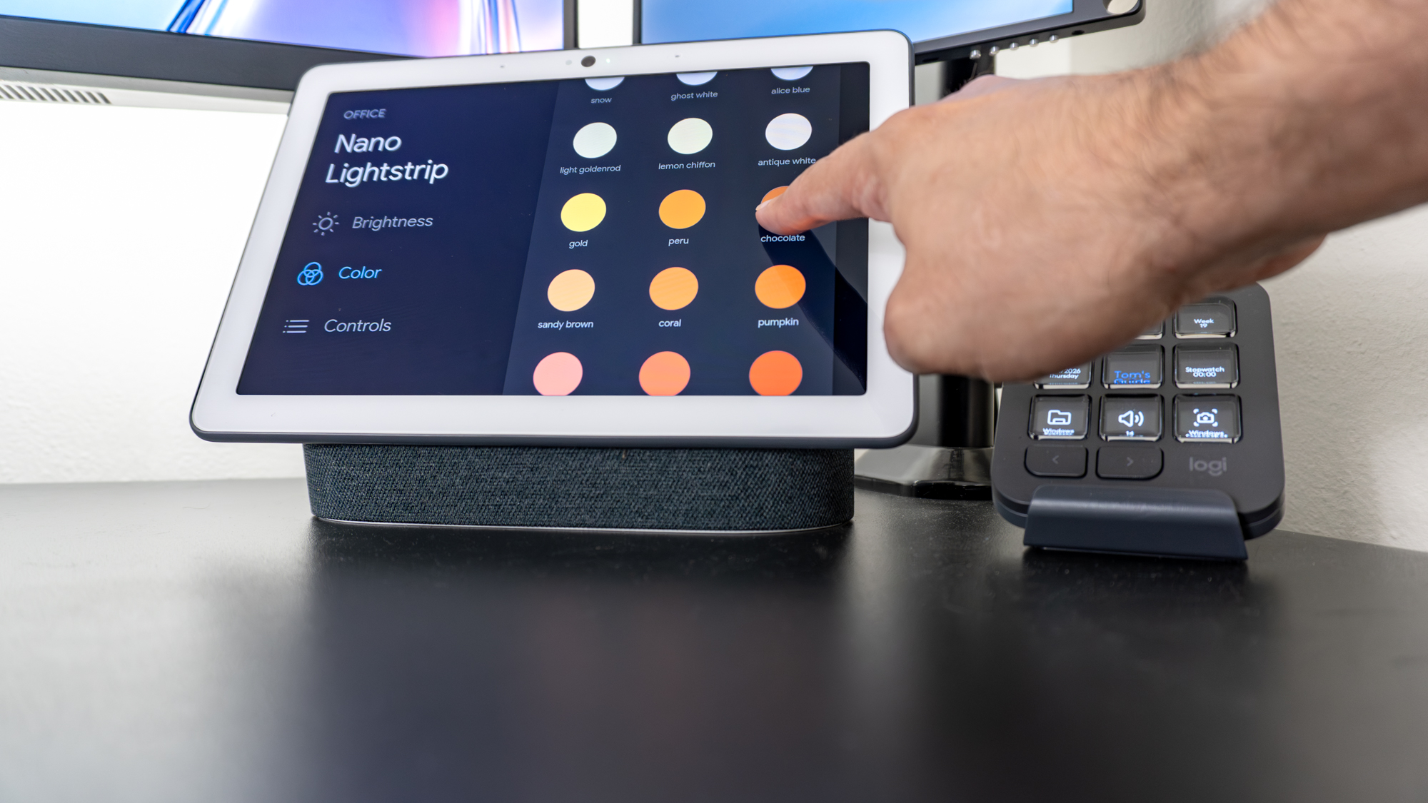 A person changing a smart light's color using the Google Nest Hub Max on a desk