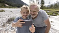 A grandfather and his granddaughter look at a tablet together.
