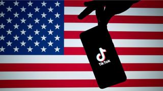Smartphone with TikTok opening screen on it in front of an American flag