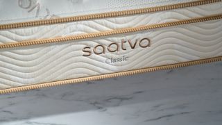 Image shows the Saatva Classic logo on the side of the mattress photographed during our review photography session