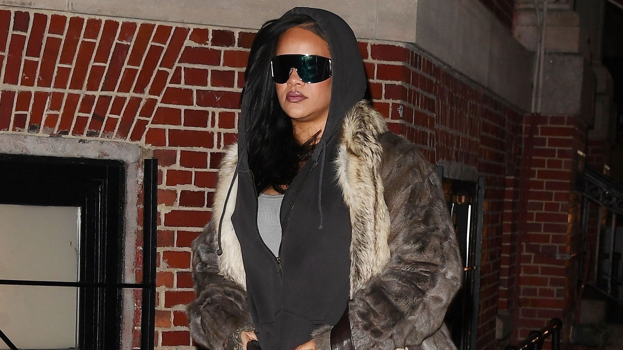 Rihanna wears snake-print boots with jeans, a fur coat, and a hoodie