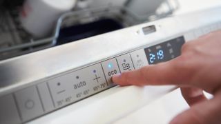 The control panel of a dishwasher with someone selecting the Eco setting