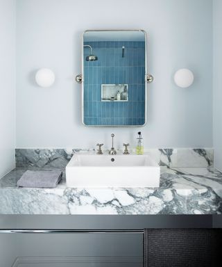 Blue painted bathroom with blue tiles, marble countertop with sink and mirror