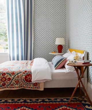 wallpapered guest bedroom with striped curtains and layered print and pattern
