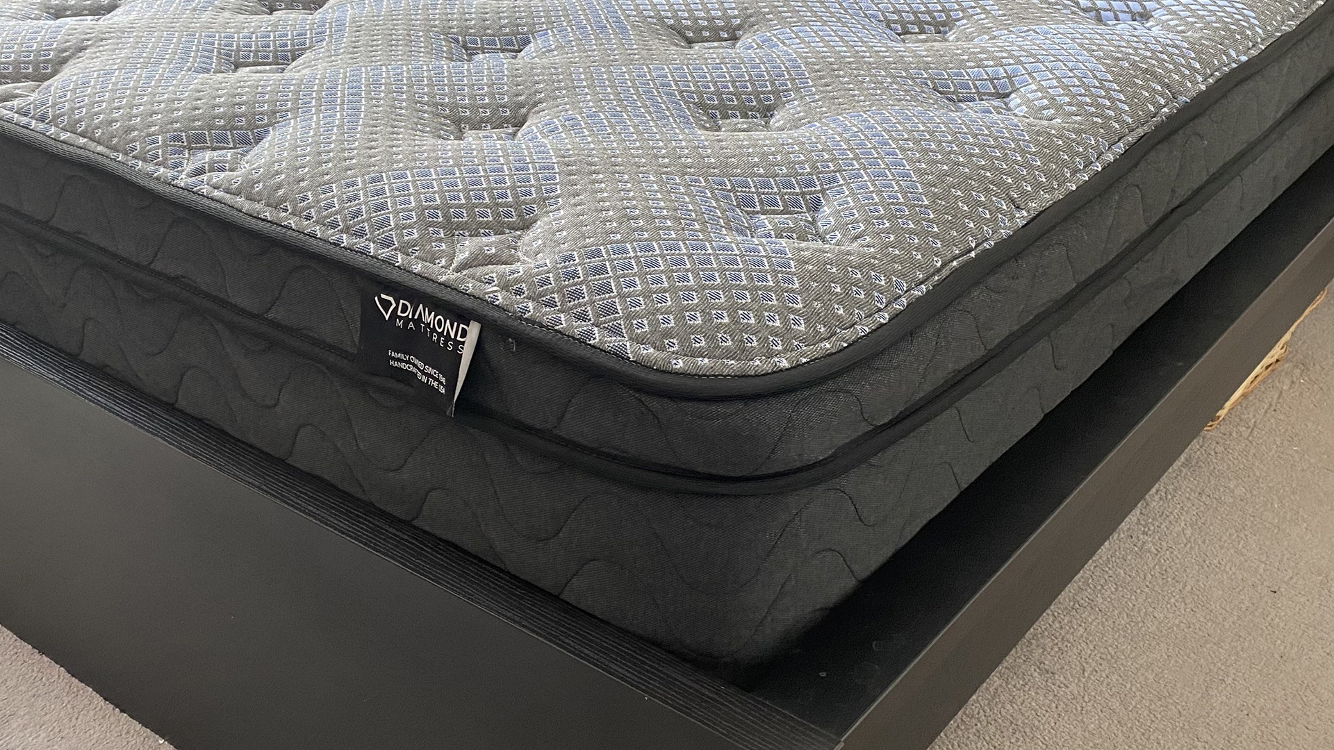 A close up of the corner of the Dreamstage Value Quilted Hybrid Mattress on a black bed frame in our reviewer's room.